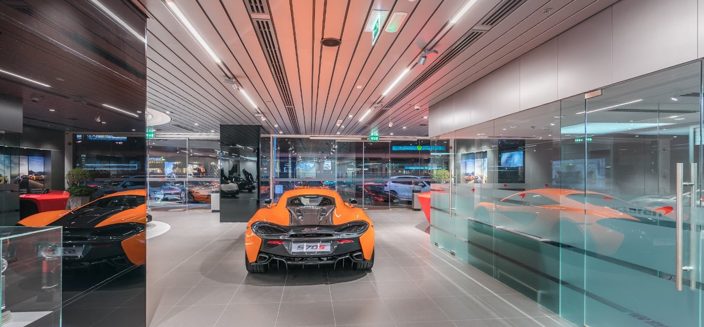 McLaren showroom with an orange 570S under a ribbed ceiling